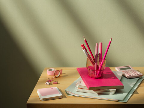 Pink stationery and school supplies neatly arranged on a wooden desk