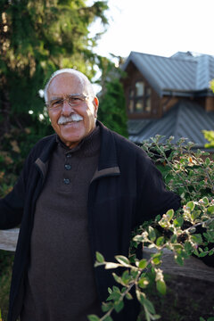 Smiling senior man outdoors in garden near home, candid portrait