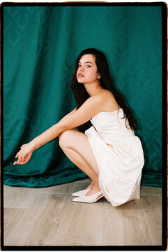 Woman squatting in white dress 