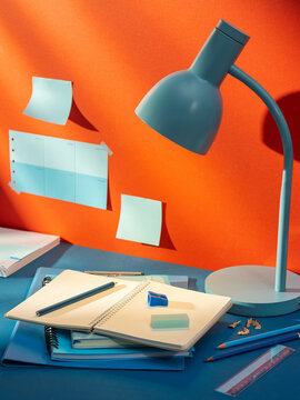 Desk lamp illuminates open notebook with pencils and stationery