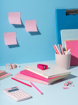 Pink and blue stationery items arranged neatly on a light blue desk