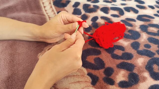  Person holding red yarn for knitting and crochet craft, hands working with fiber thread, handmade hobby.