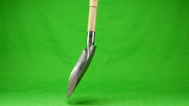 Garden Trowel on Green Screen: A close-up shot focuses on a sturdy metal garden trowel with a wooden handle, set against a vibrant green backdrop, perfect for compositing into various scenes.