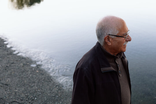 Candid portrait of a senior man standing by a calm lake shore