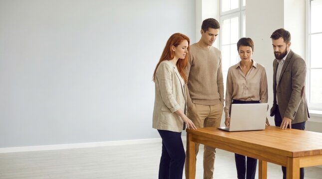 Diverse Group of Young Professionals Collaborating and Reviewing Project Data on a Laptop in a Modern Minimalist Office Environment