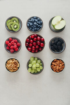 Healthy antioxidant rich fruits, berries and nuts on light background