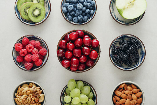 Healthy antioxidant rich fruits, berries and nuts on light background