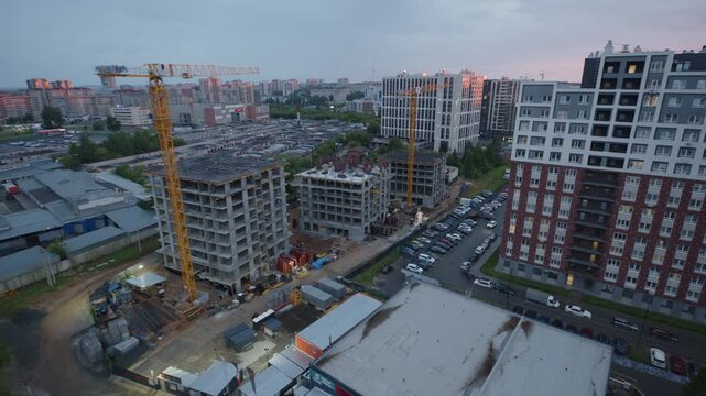 Aerial view of a construction site with tower cranes and apartment buildings in the city of Izhevsk, Russia, at dusk