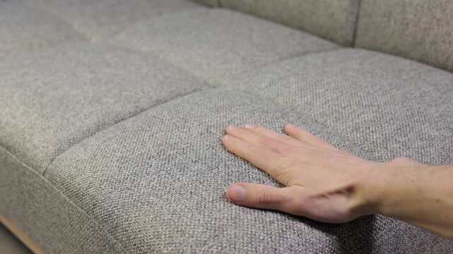 Man is touch furniture and choosing softest of sofa in furniture store.