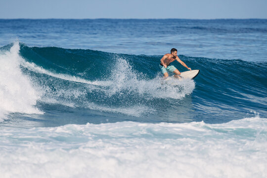 Athletic surfer riding a powerful ocean wave on a sunny day