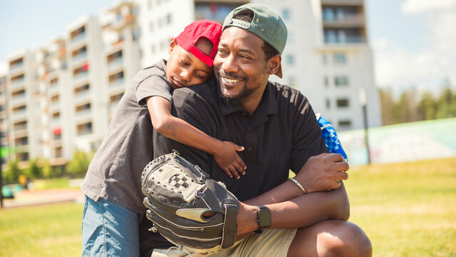 Father and son playing baseball in sunny day at public park