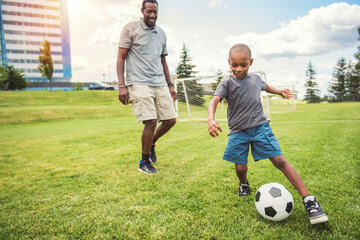 Obraz premium father with son playing football or soccer outside on field