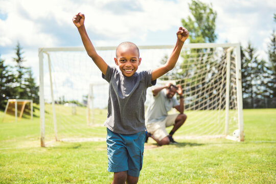 father with son playing football or soccer outside on field
