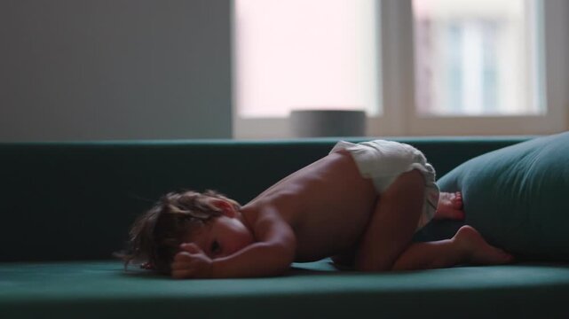 Toddler diving into sofa cushion during indoor play at home, expressing carefree joy, imagination and active childhood development