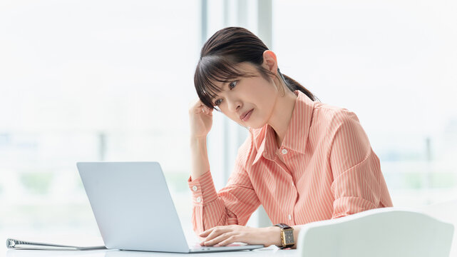 パソコンを使いながら考える女性・ビジネスウーマン, Businesswoman Thinking While Using a Laptop