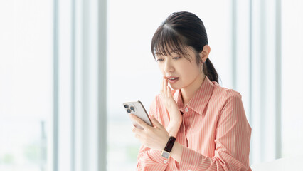 スマートフォンを見て驚く女性・ビジネスウーマン, Surprised Businesswoman Looking at a Smartphone © Trickster*