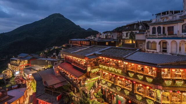 Dusk to night timelapse showing tourists visiting the famous Old Street shops and teahouses in Jiufen, New Taipei City, Taiwan, zooming in. 