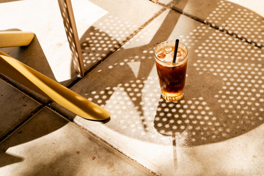 High angle view of iced espresso tonic glass on a concrete floor with patterned shadow