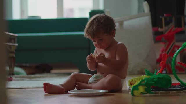 Toddler eating chicken while sitting on floor at home, encouraging independent eating, healthy nutrition and everyday childhood development