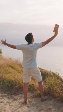 vertical Man enjoying freedom with a passport on a cliff at sunset