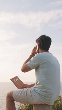 vertical Remote worker planning his next travel adventure by the sea