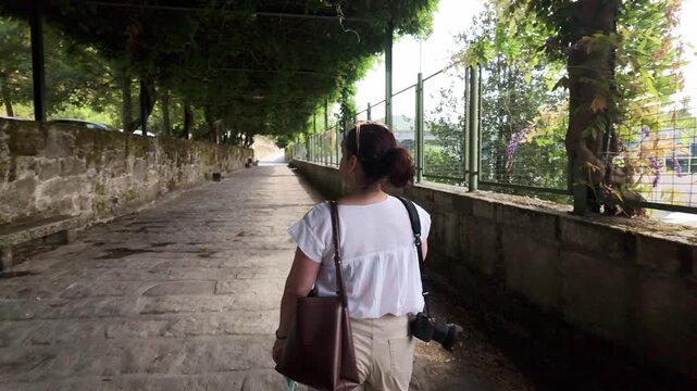 Female photographer walking down a shaded historic stone path