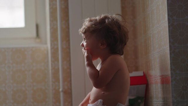 Toddler eating snack while seated in kitchen at home, encouraging healthy nutrition, independence and everyday childhood routine
