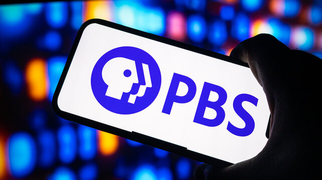 PBS logo on smartphone screen with vibrant bokeh lights background television and education concept.