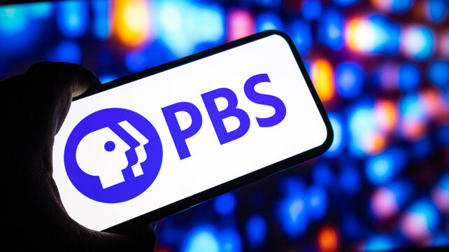PBS logo on smartphone screen with vibrant bokeh lights background television and education concept.