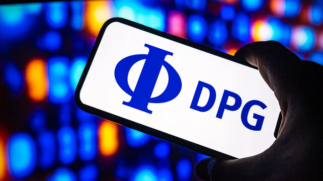 Dpg media logo on smartphone screen held in hand against colorful bokeh background representing digital news and media.
