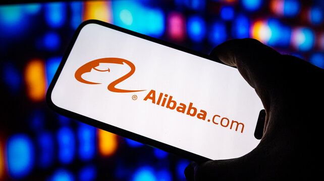 Alibaba com logo on smartphone screen held by person against colorful bokeh background symbolizing e-commerce and global online retail.