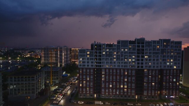 Lightning flashes over the buildings in a city. Rain and thunder storm over the city.