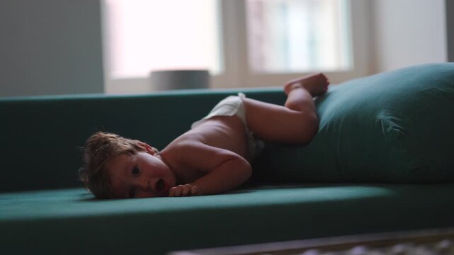 Toddler inventing games on sofa cushions at home, expressing imagination, active movement and joyful childhood independence