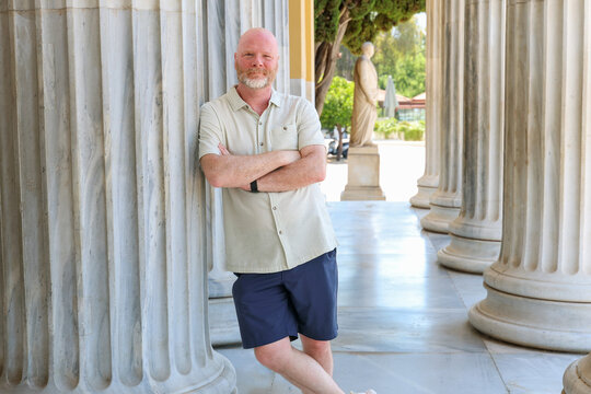 Man standing among classical marble columns at a historic site in Greece, blending travel, architecture, culture, and timeless Mediterranean heritage.