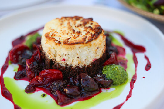 Baked cheese served with berry compote and herb sauce, presented as an upscale Mediterranean dish at a restaurant in Greece.