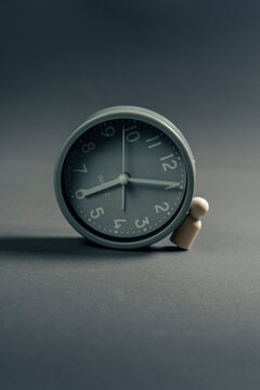 Wooden figurine supporting a clock as a concept of time pressure and deadlines