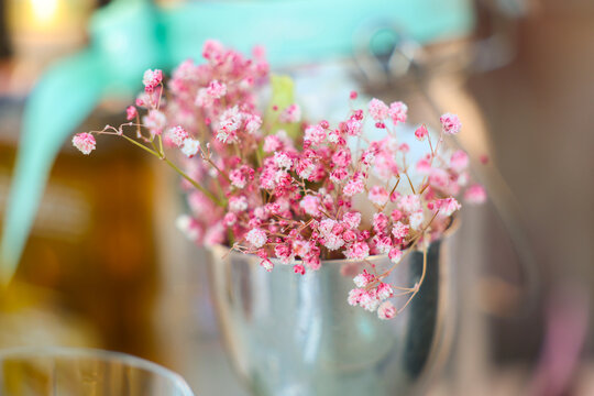 Delicate pink flowers arranged in a small metal vase, creating an elegant table decoration with soft colors and shallow depth of field.