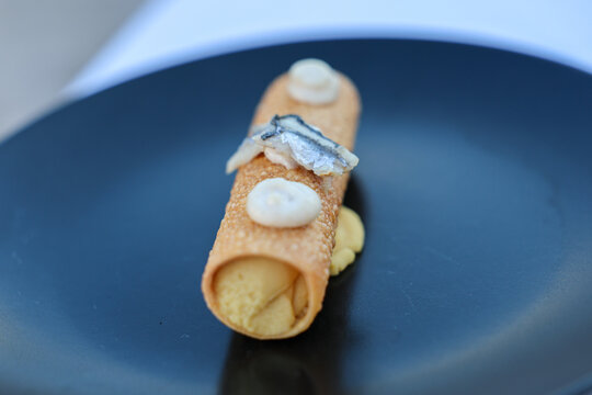 Crisp pastry filled with creamy fava bean puree and topped with anchovy, served as an elegant Mediterranean appetizer at a restaurant in Greece.
