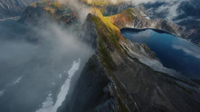 FPV Drone Flying Over Sharp Mountain Peak Towards Misty Alpine Lakes