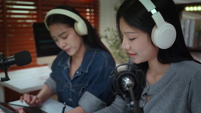 Podcast podcaster recording studio microphone headphone content influencer creator collaboration capture two female hosts planning show in home studio, calm conversation with joy, recording interview