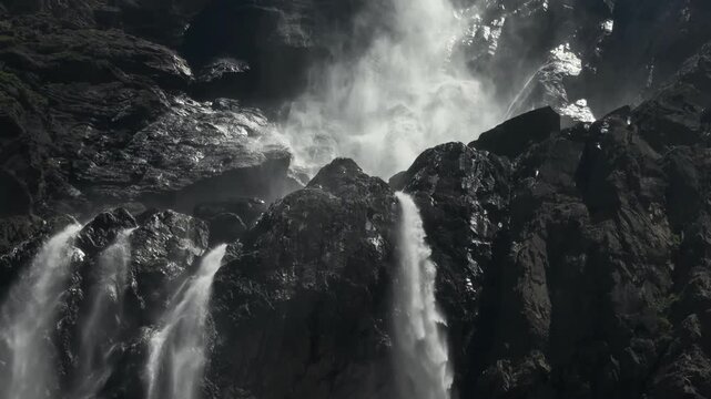 Wide waterfall over dark mountain boulders