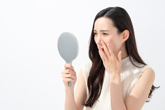 鏡を見て鼻を気にする女性