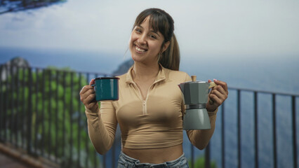 Obraz premium Woman holding teal mug and moka pot, smiling while offering cups on a balcony overlooking ocean and cliff; serenity morning ritual.