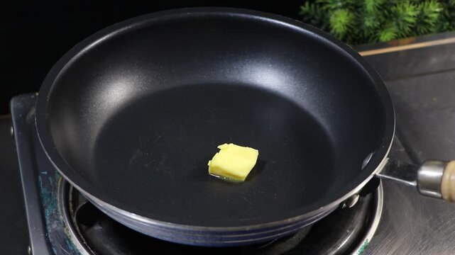 Adding butter to a frying pan and mixing with a spatula
