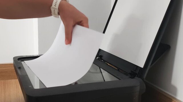 Hand removes scanned document from flatbed scanner after digitization process. Administrative tasks support efficient office routine, while organized administrative tasks improve document workflow.