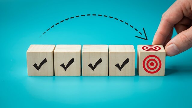 Hand placing a wooden block with a target symbol next to completed checkmarks