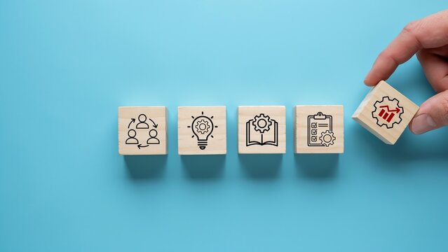 Hand placing a wooden block with a growth chart icon on a blue background