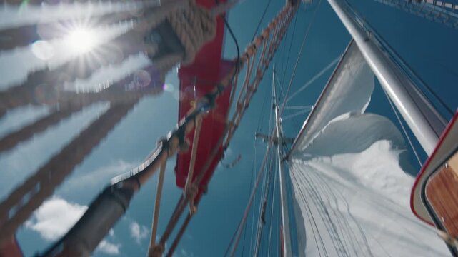 Old captain controls the crew working with the sails on the big expeditional sailing vessel moving in the Atlantic Ocean