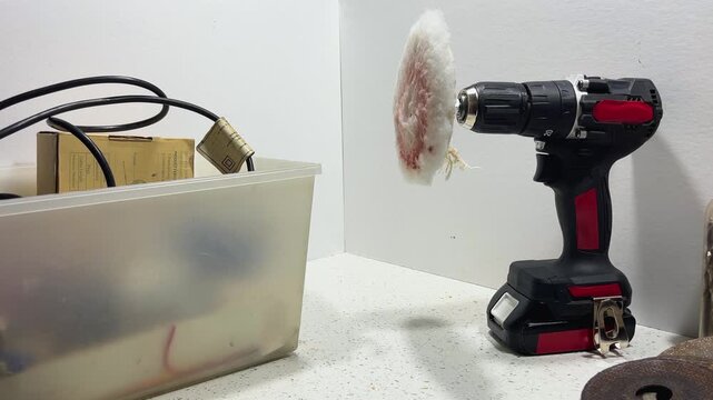 Cordless electric drill with a soft polishing pad attachment on a white countertop.