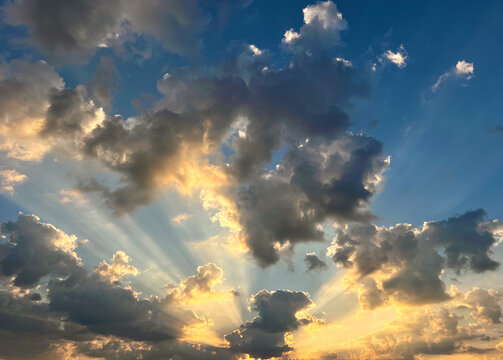 Sunbeams radiating through clouds in a blue sky